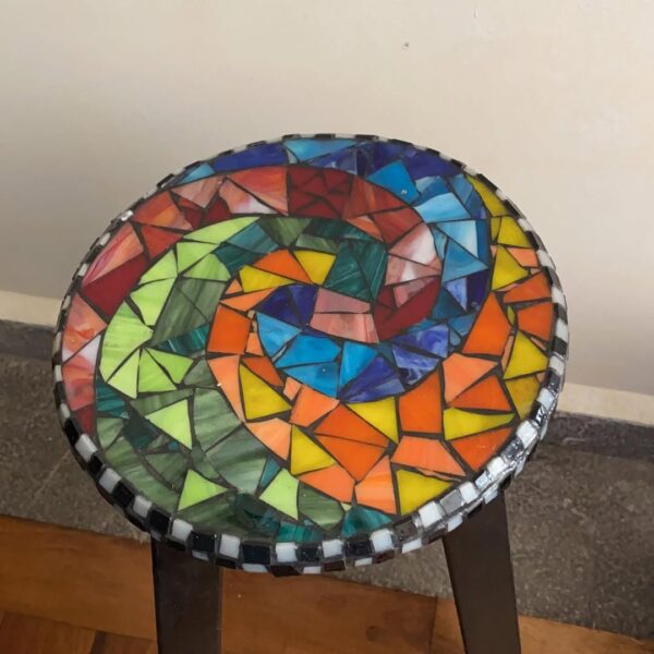 Mesa de mosaico colorido con un taburete encima, creando un contraste vibrante y atractivo.