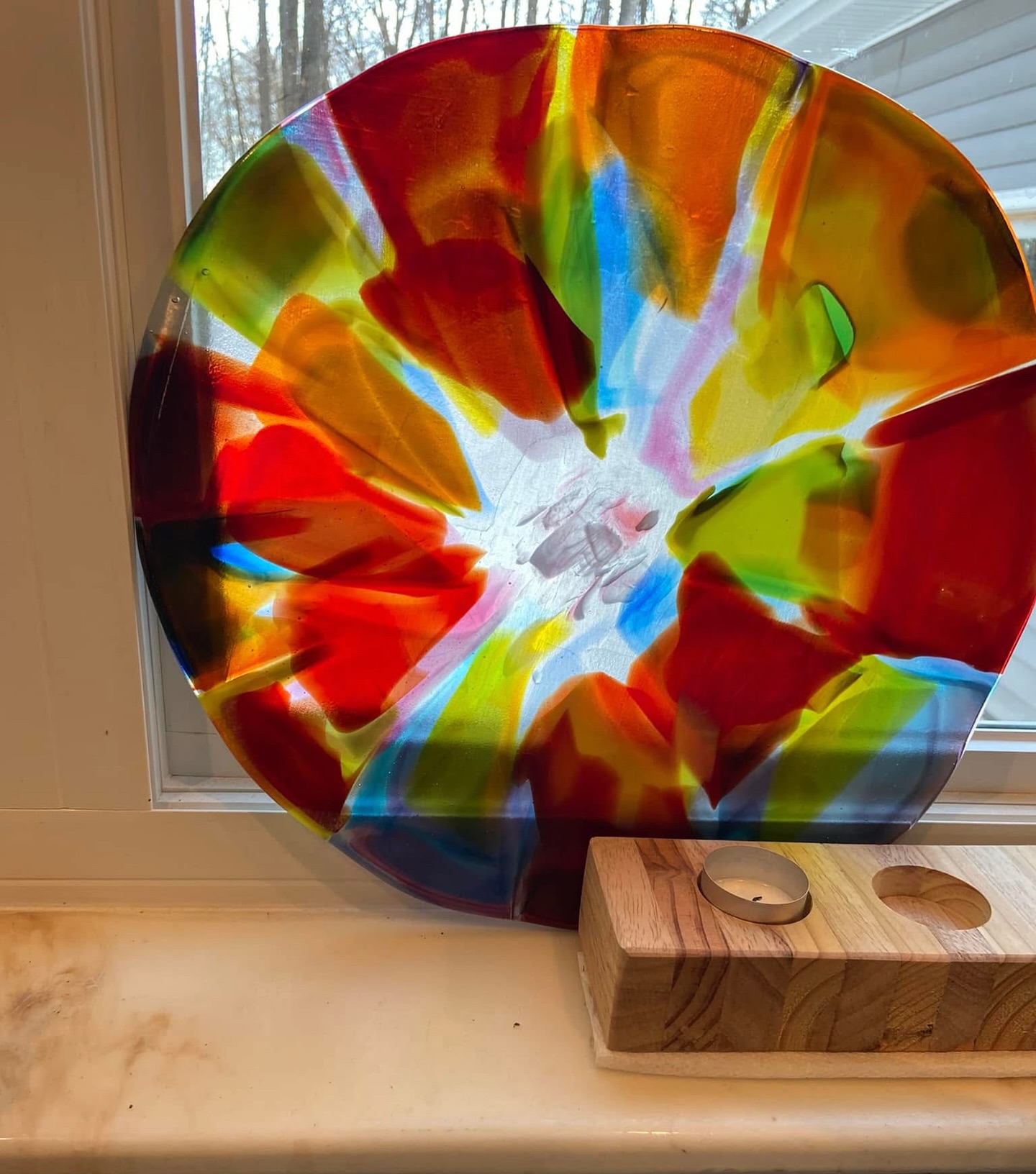 Plato de vidrio colorido sobre una encimera, al lado de un bloque de madera.