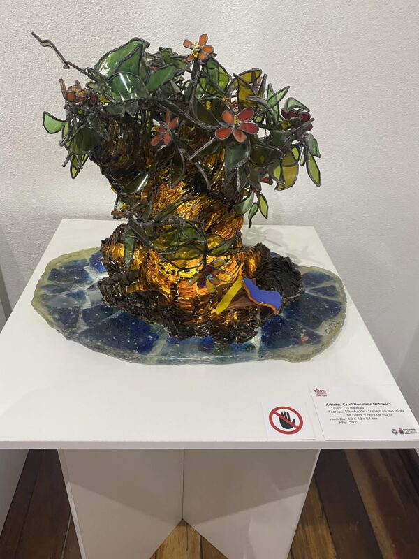 Escultura de vidrio de un árbol con flores y pájaros, mostrando belleza y delicadeza en su diseño.